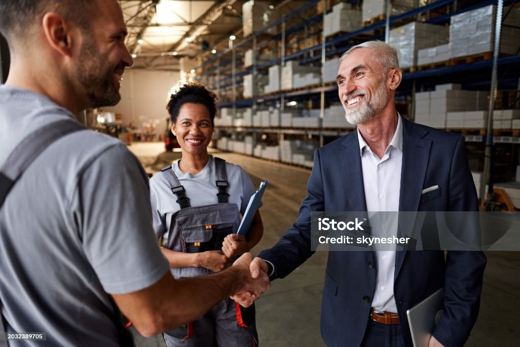 Vendor and Officer shaking hands in a warehouse. 