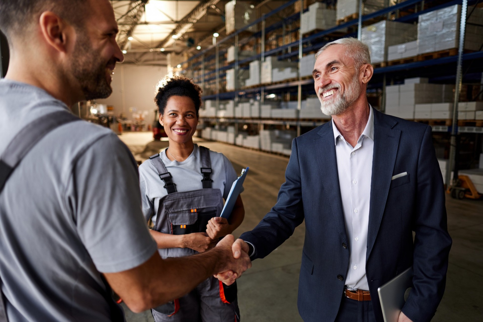 A vendor shaking hands with a business man in a warehouse. 
