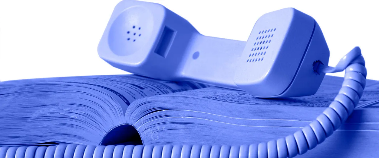 An image of a phone receiver resting on an open "Yellow Pages" book that has been retouched so that it's blue in color.
