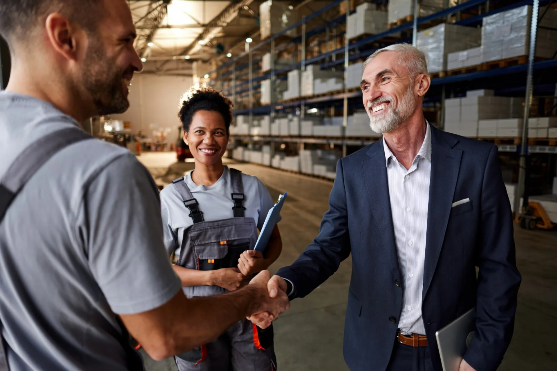 A vendor shaking hands with a business man in a warehouse. 